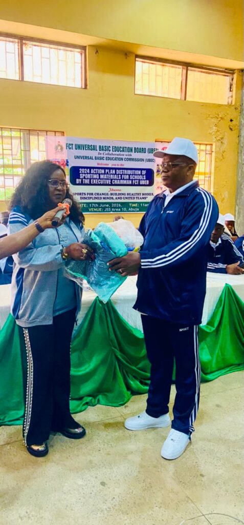 Wenegieme doing a symbolic presentation of nthe sporting equipment